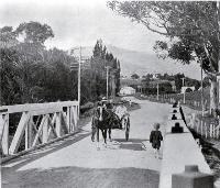 Horse and buggy crossing the bridge : looking up towards the Wairewa Valley from Little River, Banks Peninsula. [1925]